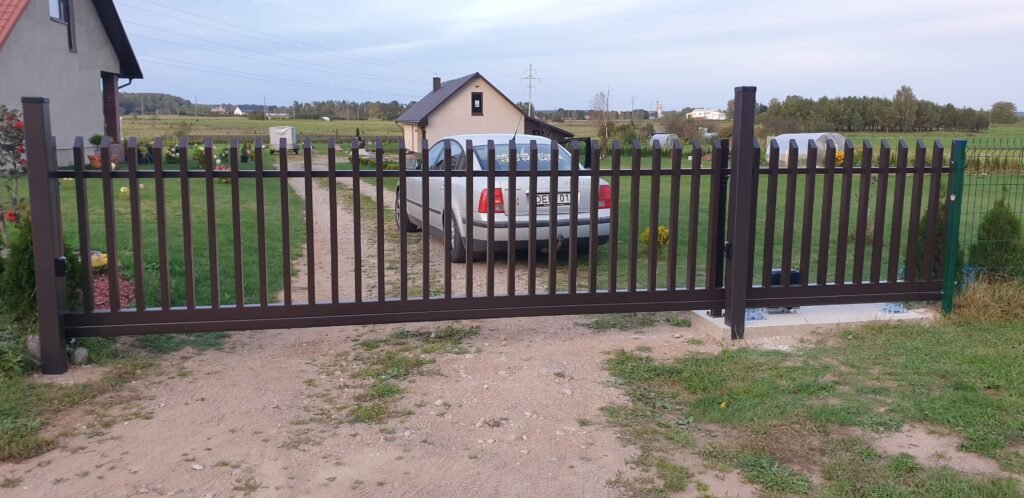 Įvažiavimas su automobiliu, stovinčiu šalia rudų šukų vartų